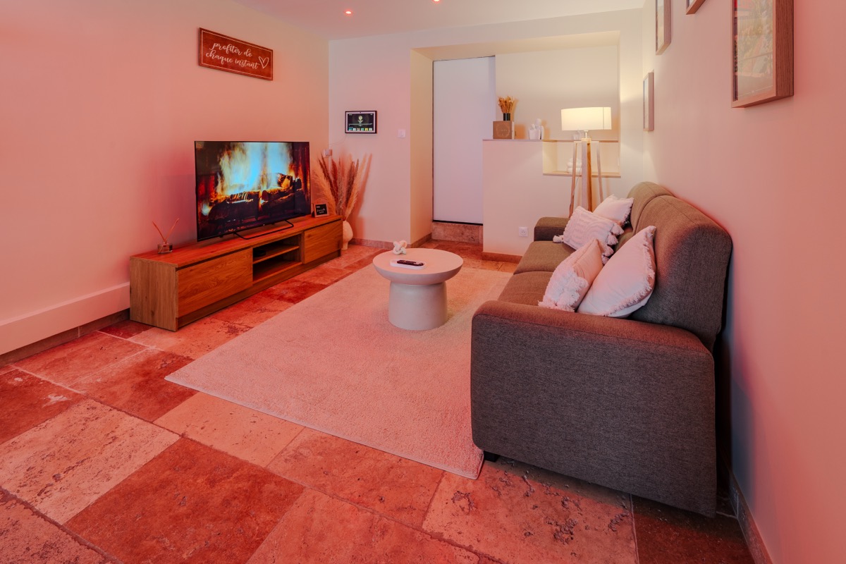 Coin salon cosy avec canapé et écran connecté — L'Inavouable, Côte d'Opale